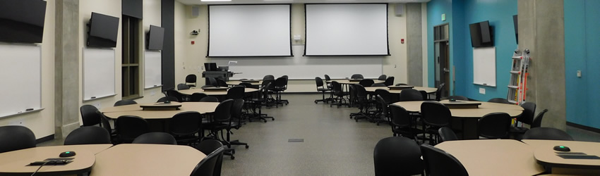 Image of SCALE-UP Classrooms (Flat Floor), known internationally as SCALE-UP, describes 9-person teams at seven foot diameter tables that allow larger discussion groups or teams of 3 students working together at user-provided laptops. Purdue’s tables are comprised of (3) 120° tables ganged around a technology hub or left loose for reconfiguration